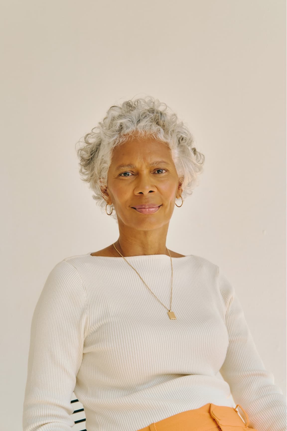 A woman with silver hair in a cream sweater, looking toward the camera